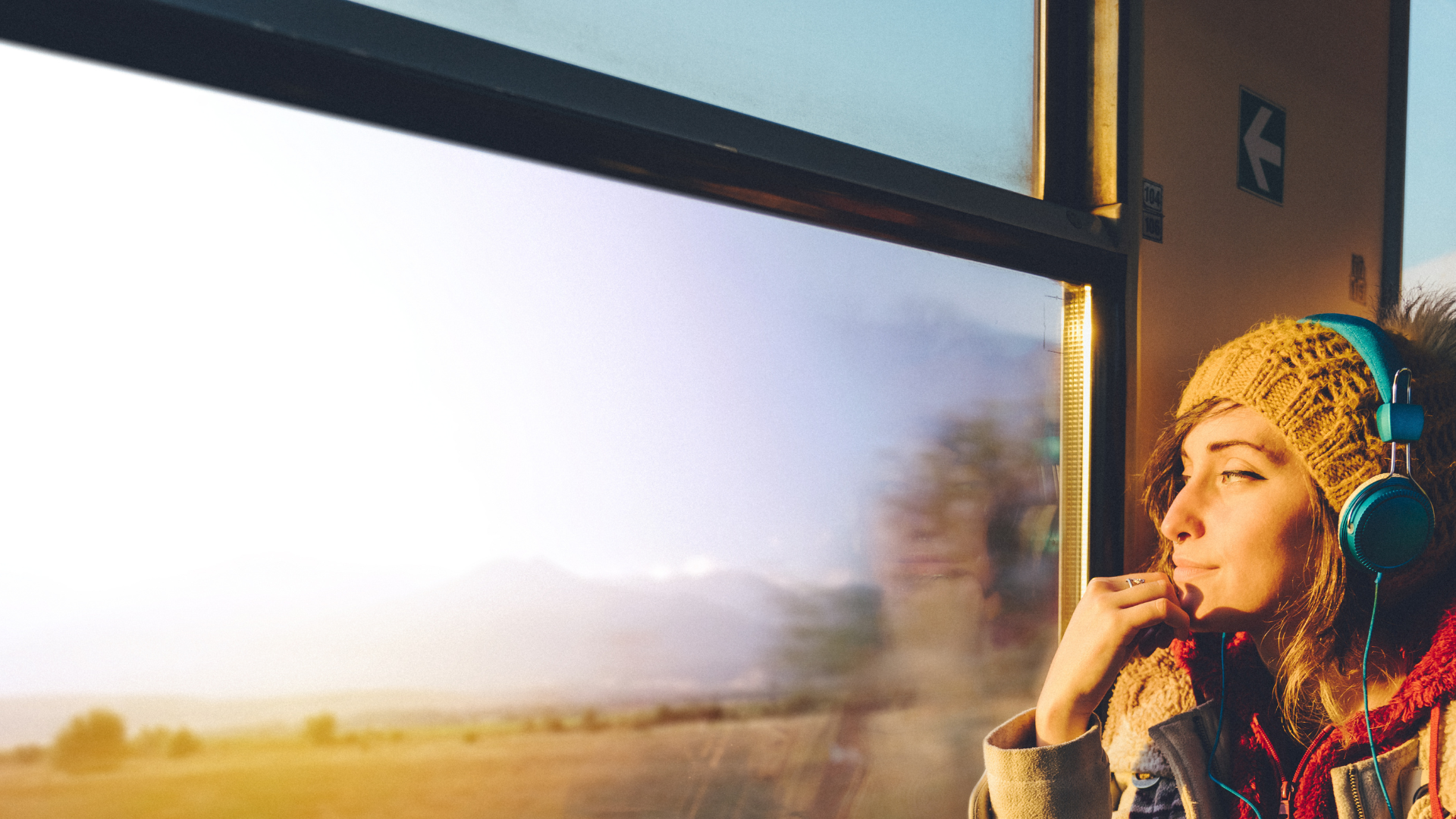 Woman listening to headphones, gazing out a train window